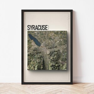 May include: Framed aerial map of Syracuse, New York, featuring the city's layout, surrounding terrain, and a large lake. The word "SYRACUSE" is printed in bold black letters at the top, with "new york" in smaller text below.