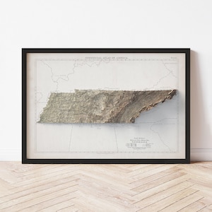 May include: Framed vintage map of Tennessee, featuring a 3D relief effect. The map is set against a cream-colored background with black text and a black frame. The map shows the state's topography and geographical features.