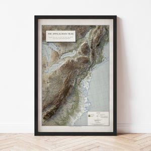 May include: Framed map print of the Appalachian Trail. The map features a detailed topographical view of the trail's route, with text that reads "THE APPALACHIAN TRAIL". The map is framed in a black border.