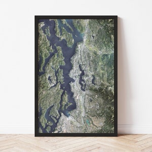 May include: A black framed poster with a satellite image of the Puget Sound region in Washington state. The image shows the water, islands, and surrounding land.