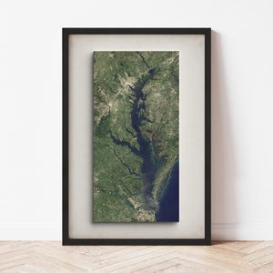 May include: A framed print of a satellite image of the Chesapeake Bay, a large estuary in the Mid-Atlantic region of the United States. The image shows the bay's intricate network of waterways and surrounding land.