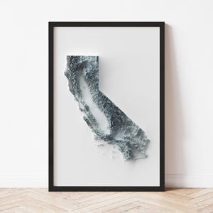 May include: A framed wall art print featuring a 3D topographical map of California. The map is in shades of gray and white, with a textured appearance. The artwork is set against a white background and framed in a black frame.