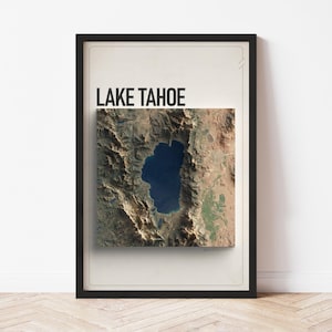 May include: A framed print featuring a detailed aerial view of Lake Tahoe, with the words "LAKE TAHOE" in bold black letters at the top. The image showcases the lake's deep blue waters surrounded by brown and green mountainous terrain.