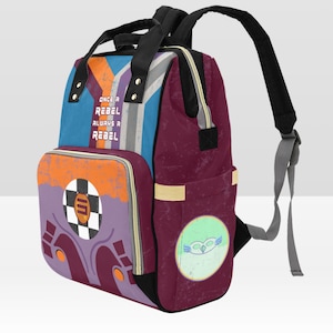 Könnte beinhalten: Ein weinroter und blauer Wickeltasche-Rucksack mit einem farbenfrohen Design. Die Tasche hat eine große Tasche auf der Vorderseite mit dem Text "Once a Rebel Always a Rebel". Die Tasche hat auch eine kleine Tasche auf der Vorderseite mit einem Cartoon-Eulen-Design.
