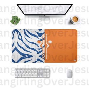 May include: A desk mat with a blue and white zebra print on the left side and a solid orange color on the right side. The mat has a white border and a small black triangle in the bottom right corner.