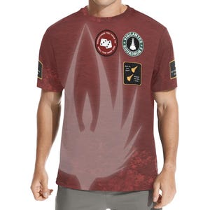 Könnte beinhalten: Bordeauxfarbenes T-Shirt mit einem großen weißen Flammendesign und mehreren Aufnähern. Die Aufnäher zeigen Text und Grafiken wie Würfel, eine Rakete und die Worte "Vigilantes Squadron 3". Das T-Shirt hat eine strukturierte Optik.