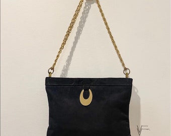 May include: A black suede clutch bag with a gold chain strap and a gold crescent moon-shaped accent on the front.