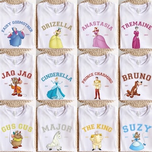 Puede incluir: Doce camisetas blancas con diferentes diseños que representan personajes de la película de Disney Cenicienta. Cada camiseta tiene el nombre de un personaje diferente y el texto "EST 1950".