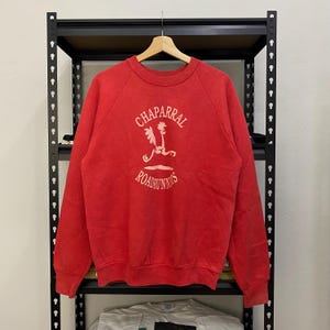 May include: Red sweatshirt with a white graphic of a running roadrunner with the text "Chaparral Roadrunners" on the front.