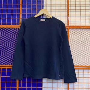 Könnte beinhalten: Ein marineblaues Langarmshirt hängt an einem Holzbügel. Das Shirt hat einen Rundhalsausschnitt und ein kleines Logo in der Nähe des Halsausschnitts. Das Shirt ist aus einem weichen, bequemen Material gefertigt.