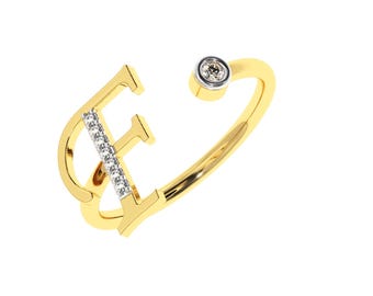 Puede incluir: Un anillo dorado con la forma de la letra "F". La letra está adornada con pequeñas piedras preciosas transparentes. Una sola piedra preciosa redonda está engastada en el extremo del anillo.