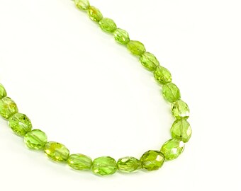 May include: A strand of green peridot beads, each bead is faceted and oval shaped.