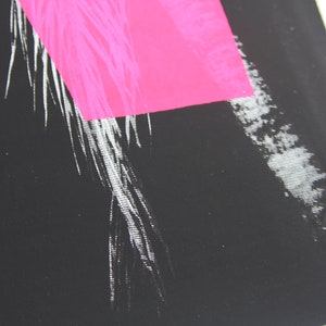 Puede incluir: Primer plano de una impresi&oacute;n abstracta en blanco y negro con un rect&aacute;ngulo rosa brillante en la esquina superior derecha.