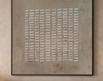May include: A square wall art piece featuring a beige, textured background with a central grid of small, raised white rectangular blocks arranged in vertical columns. The artwork is enclosed in a thin, dark frame and hangs above a bed.