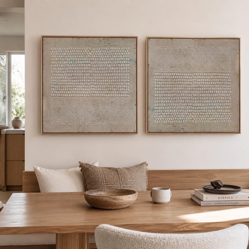 Puede incluir: Dos obras de arte abstractas enmarcadas en tonos neutros. Cada pieza presenta un fondo gris claro texturizado con un patr&oacute;n de peque&ntilde;os puntos y l&iacute;neas blancas. Los marcos son de un c&aacute;lido tono de madera natural. La obra de arte cuelga sobre una mesa de madera.