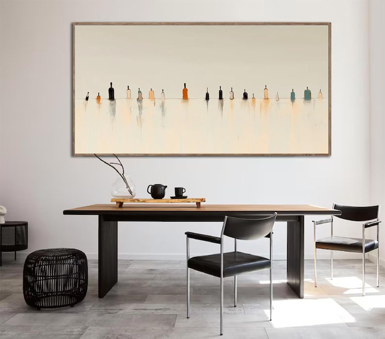 May include: A long, horizontal abstract painting with a white background and a row of colorful, vertical shapes in the center. The shapes are reminiscent of bottles or jars, and they are reflected in the water below. The painting is framed in a light wood frame.