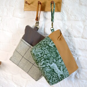 May include: Two fabric bags with brown leather straps. The bag on the left is a gray and white plaid pattern. The bag on the right is a green and white floral pattern with a brown top.