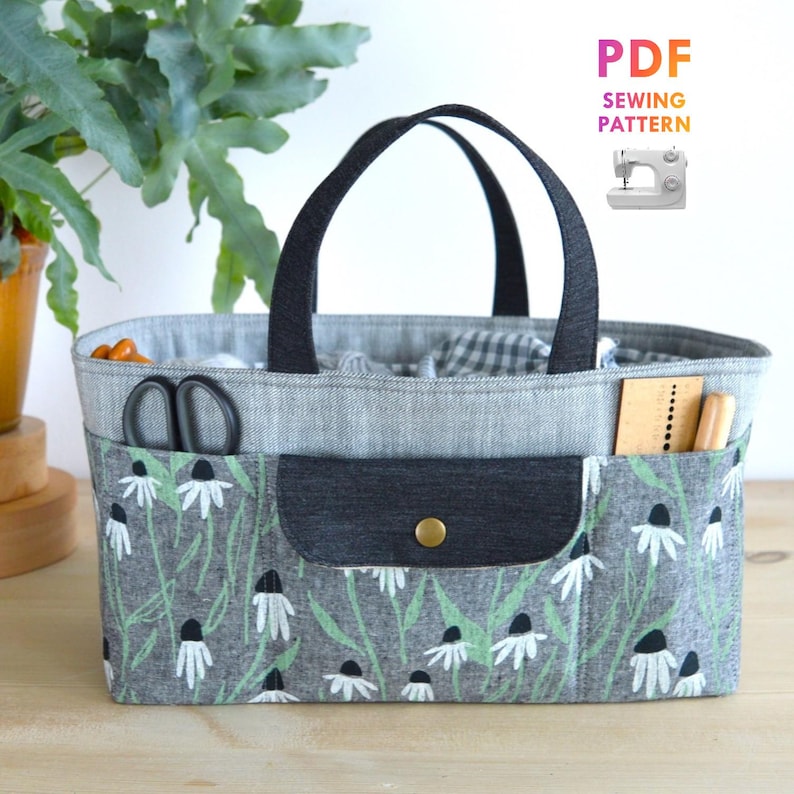 May include: A rectangular sewing basket with a gray floral print pocket and black handles. The basket contains sewing tools and fabric. The text "PDF Sewing Pattern" is in the upper right corner.