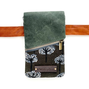Puede incluir: Un bolso bandolera rectangular con un estampado de bosque y una solapa verde oscuro. El bolso tiene cierre de cremallera y una correa de cuero marr&oacute;n. El texto "KANDOU CRAFTS" est&aacute; en una etiqueta de cuero.