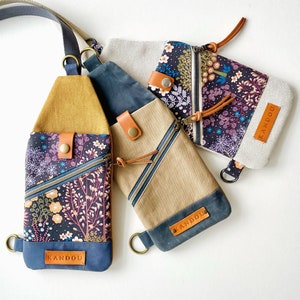 May include: Three fabric bags with floral patterns and the word "KANDOU" printed on them. The bags have brown leather straps and buckles.