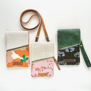 Puede incluir: Tres peque&ntilde;os bolsos cruzados de colores con cremalleras diagonales y detalles de cuero. Una bolsa presenta estampados florales naranjas, otra dise&ntilde;os florales rosas y la tercera tiene una parte superior verde y un estampado de bosque. Cada bolsa tiene una etiqueta "KANDOU".