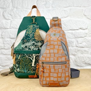 May include: Two backpacks, one green with a floral pattern and one orange with a geometric pattern. Both backpacks have adjustable straps and zipper closures.