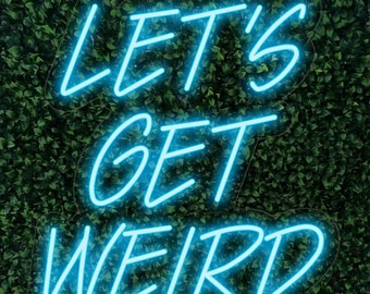 May include: A neon sign with the words "LET'S GET WEIRD" in bright blue against a backdrop of green foliage. The sign's glowing letters create a vibrant and eye-catching display, perfect for adding a touch of fun to any space.