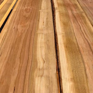 以下が含まれることがあります： 木目の2つの部分のクローズアップで、自然な木目のパターンと色の変化を示しています。木は薄い茶色で、濃い茶色の筋と節があります。