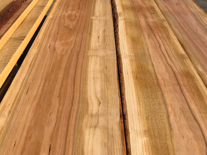 以下が含まれることがあります： 木目の2つの部分のクローズアップで、自然な木目のパターンと色の変化を示しています。木は薄い茶色で、濃い茶色の筋と節があります。