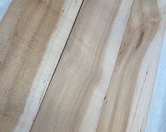 May include: Three light brown wooden boards with a natural wood grain pattern.