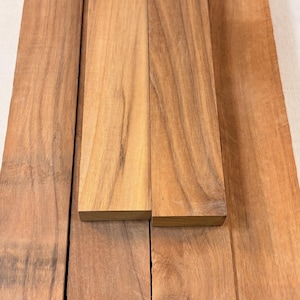 May include: A collection of unfinished hardwood boards, showcasing natural wood grain patterns. The boards vary in size and are a warm, reddish-brown color. Ideal for woodworking projects, these boards offer a rustic aesthetic.