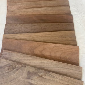 May include: A stack of eight wood veneer sheets in various shades of brown. The sheets are arranged in a staggered pattern, with the largest sheet at the bottom and the smallest sheet at the top.