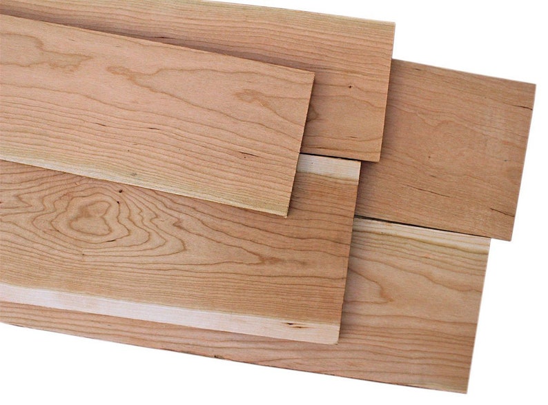 以下が含まれることがあります： 異なる木目模様の、未仕上げの桜材が4枚。木の色は薄い茶色で、表面は滑らかです。