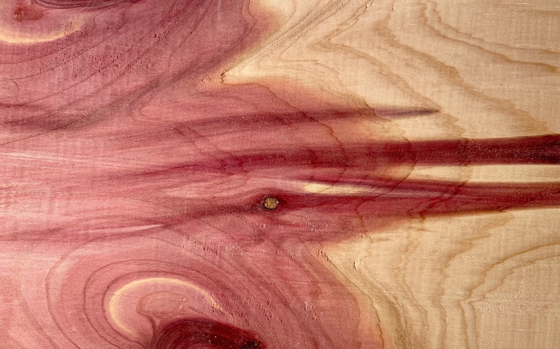 May include: Close-up of a piece of wood with a reddish-brown color and a swirling grain pattern. The wood has a natural, rustic look.
