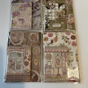 May include: Four packs of decorative paper sets with vintage floral and butterfly designs. Each pack features different patterns, including botanical prints, window scenes, and a dress form. The colour palette includes soft pinks, greens, and purples.