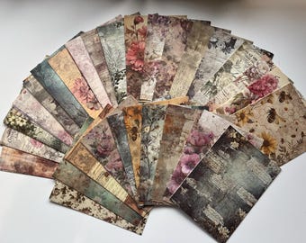May include: A collection of vintage-style scrapbook paper sheets fanned out. The papers feature floral, botanical, and bee-themed designs in muted colors like beige, brown, and pink. Some sheets have text overlays, creating a layered, antique aesthetic.