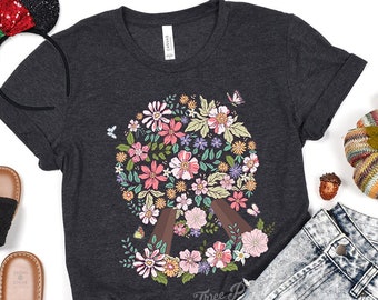May include: A dark grey t-shirt with a peace sign design made of flowers. The peace sign is surrounded by butterflies and the text "Three P" is visible at the bottom.