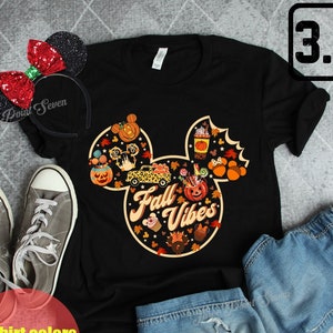 May include: Black t-shirt with a Mickey Mouse head design featuring fall-themed elements like pumpkins, leaves, and a car. The text "Fall Vibes" is written inside the Mickey Mouse head.