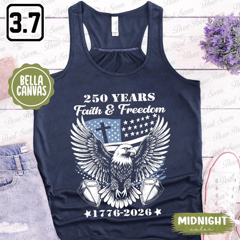 Puede incluir: Camiseta sin mangas azul medianoche con un dise&ntilde;o patri&oacute;tico. Presenta un &aacute;guila con las alas extendidas, una cruz y estrellas y rayas, con el texto "250 YEARS Faith & Freedom 1776-2026". Hecho por Bella Canvas.