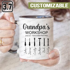 May include: White ceramic mug with a black interior and handle, printed with "Grandpa's WORKSHOP" and tool illustrations. The mug includes the text "OPEN 24/7 - TOYS FIXED FOR FREE" and customizable names. A "3.7" graphic is in the upper left corner.