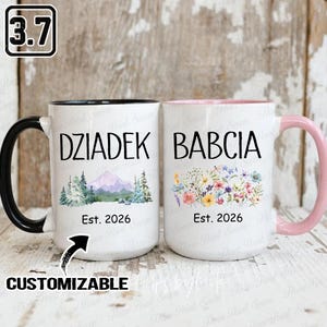 May include: Two white ceramic mugs with black and pink handles. One mug says "Dziadek" with a mountain and tree design, the other says "Babcia" with a floral design. Both mugs have "Est. 2026" printed on them. The word "CUSTOMIZABLE" is also printed on the mug.