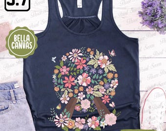 May include: A navy blue tank top with a floral design in the shape of a circle. The flowers are in shades of pink, purple, yellow, and green. The design is centered on the front of the tank top.