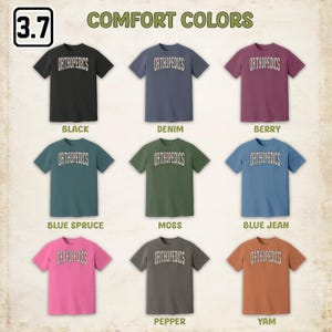 May include: Nine t-shirts in different colors, each with the word "ORTHOPEDICS" printed on the front. The colors are black, denim, berry, blue spruce, moss, blue jean, pepper, and yam.