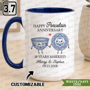 May include: A white ceramic mug with a navy blue interior and handle. The front features the text HAPPY PORCELAIN ANNIVERSARY, 18 YEARS MARRIED, Henry & Sophia, and 09.13.2008, alongside a graphic of a blue and white bowl and plate holding hands.