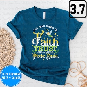 May include: Teal blue t-shirt with a yellow and green graphic that says "All you need is Faith Trust and a little Pixie Dust". The graphic also features a cartoon fairy with green wings and a yellow dress.