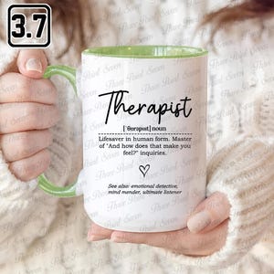 May include: White ceramic mug with a green handle and rim. The mug displays the word "Therapist" in black script, a definition, and related terms. A heart symbol is below the definition.