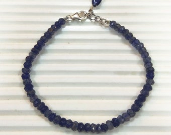 May include: A delicate bracelet made of small, dark blue gemstone beads with a silver clasp.