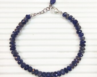May include: A silver bracelet with a clasp and a row of dark blue gemstone beads.