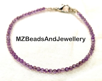Puede incluir: Delicada pulsera de cuentas de amatista morada. Las pequeñas cuentas facetadas son de color púrpura claro. El texto "MZBeadsAndJewellery" está impreso en negro.