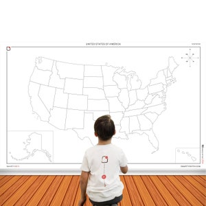 May include: A child stands in front of a large blank map of the United States. The map is divided into states and includes Alaska and Hawaii. The map is labeled "United States of America" and "50 States".